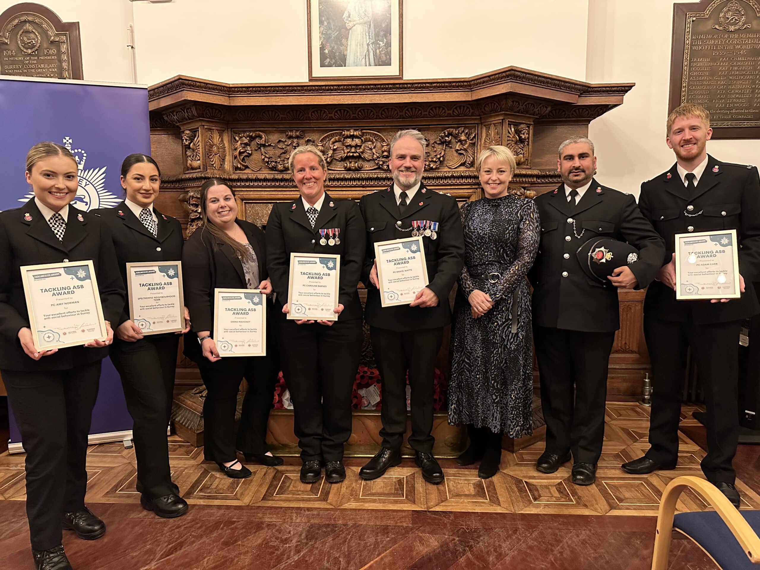 Surrey's Police and Crime Commissioner, Lisa Townsend, stands in a line alongside a group of officers in uniform holding awards. To her left, in dress uniform, is Spelthorne Borough Commander Matt Walton